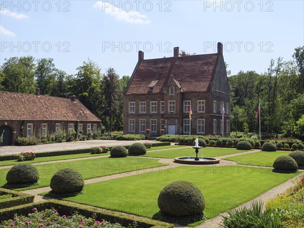 Large manor house with magnificent gardens and fountain, framed by trimmed bushes and manicured