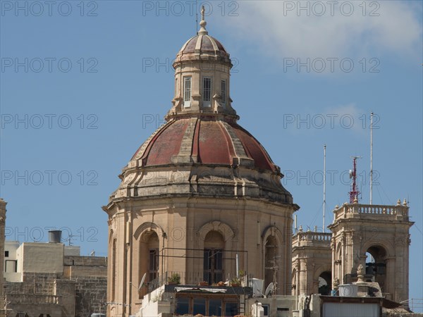 A historic church tower with a domed roof rises up under a blue sky, valetta, mediterranean sea,