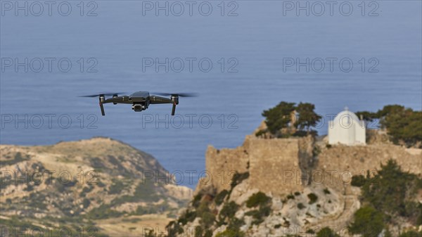 Drone flies over a castle ruin with chapel on a rock in front of the wide sea, Chapel of Saint