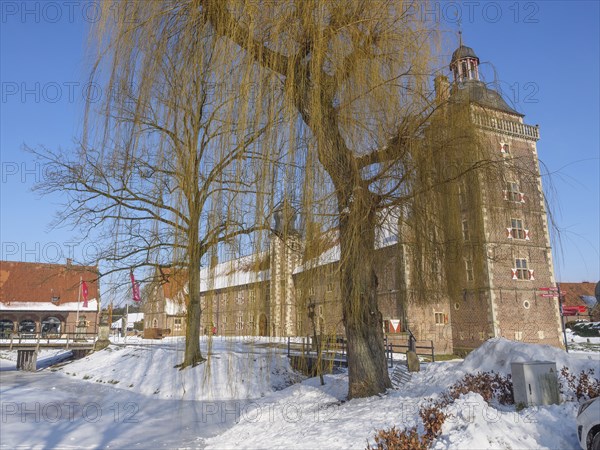 Castle in winter, next to a large willow tree, surrounded by snow and a clear blue sky, Raesfeld,