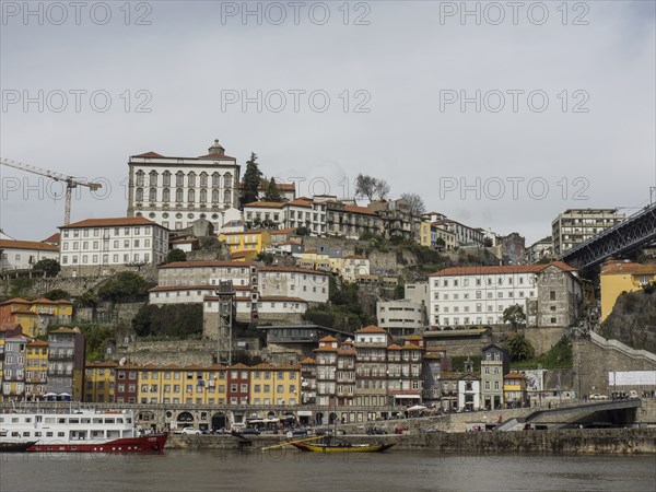 Riverside buildings stretch up the slopes of a hill, with overhanging cloud cover, Porto, Douro,