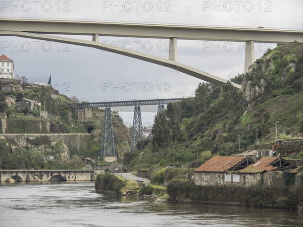 Two bridges over a valley with a river and surrounding nature under a cloudy sky, Porto, Douro,