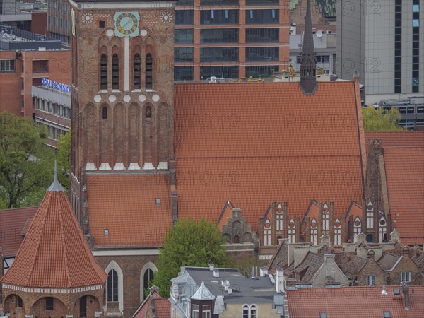 Brick church tower against a backdrop of modern architecture and skyscrapers, Gdansk, Poland,