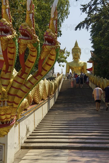 Golden Buddha statue at the top of a wide staircase, flanked by golden dragon figures, Pattaya,