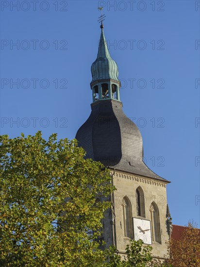 Close-up of a church tower with a clock and green dome in front of a blue sky, nottuln,
