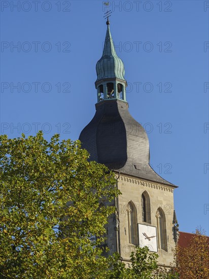 Close-up of a church tower with a clock and green dome in front of a blue sky, nottuln,