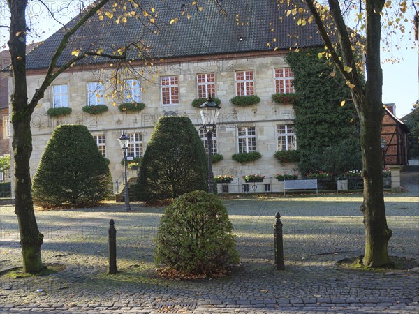 Historic building, surrounded by trees and bushes in autumn foliage, peaceful atmosphere on