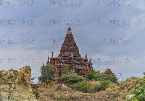 Brick stupa with behind green trees at the Irrawaddy river