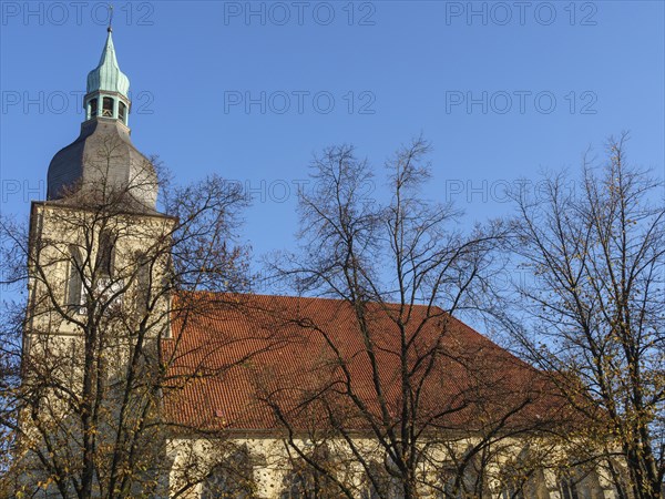 Church tower with clock and red roof tiles, surrounded by autumnal trees, nottuln, münsterland,