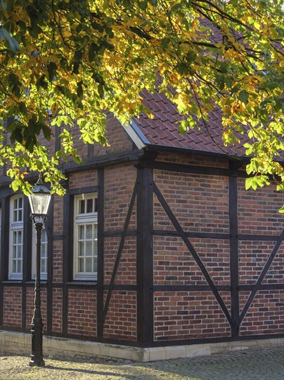 Half-timbered house with brick walls and lantern, surrounded by autumn leaves, nottuln,
