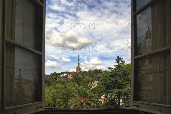 Vatican gardens seen through a window of the museum with a reflection of the basilica