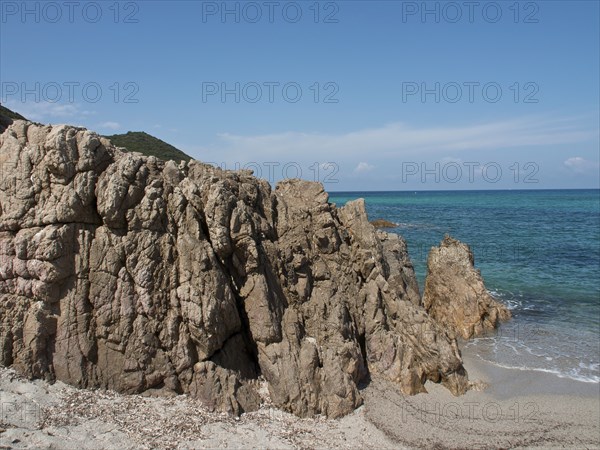 Rocky cliffs on a sandy beach with blue sea under a clear sky, ajaccio, corsica, france