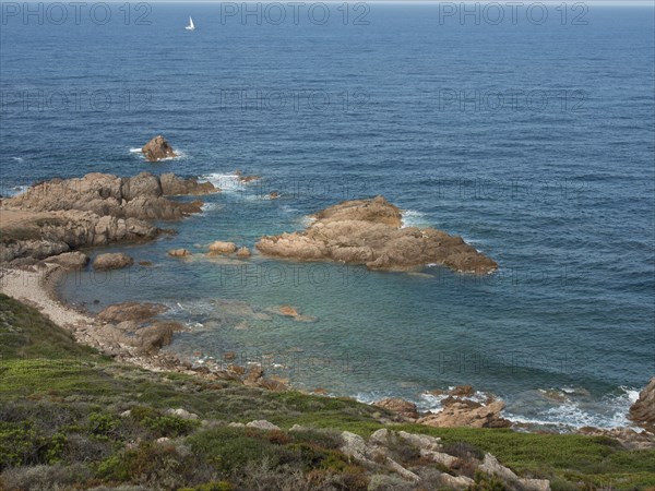 Clear blue water lapping various rocks along the coast under an expansive sky, ajaccio, corsica,