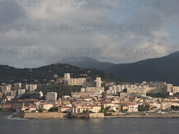 Coastal town with many buildings, mountains in the background and sunny sky, ajaccio, corsica,