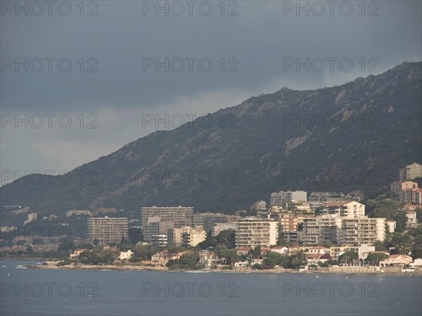 City on the coast with mountains in the background, partly cloudy sky and many buildings along the