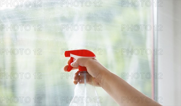 Employee cleaning window pane, spray water and soap, swab dusty and dirty glass, housework