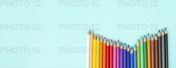 Color pencils collection in a row, back to school, drawing supplies, blue background with copy
