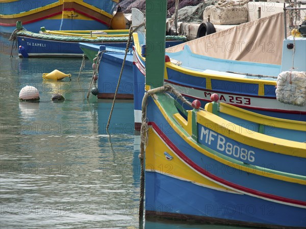 Colourful boats moored close together in a harbour, with ropes and buoys, marsaxlokk, mediterranean