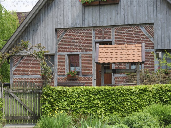 A traditional half-timbered house with red brick and wooden elements, framed by a well-tended