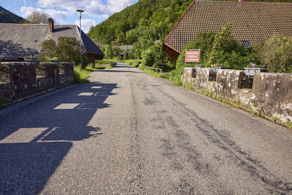 Old bridge with stone walls, flower boxes, road and Black Forest houses in the historic district of