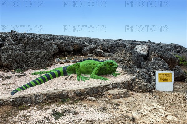 Sculpture figure of artificial oversized iguana in front of rocky terrain at the beginning of Boka