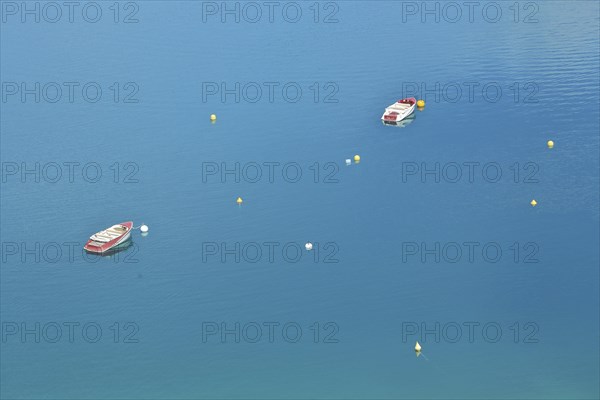 Two boats and buoys in the reservoir Lac de Sainte-Croix in the turquoise water near