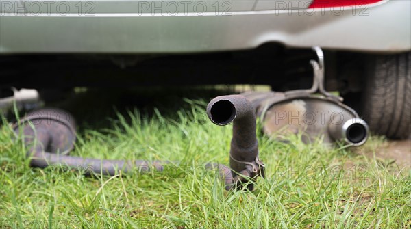 Broken exhaust and muffler of a car, rusted silencer fallen down on the road, breakdown of vehicle