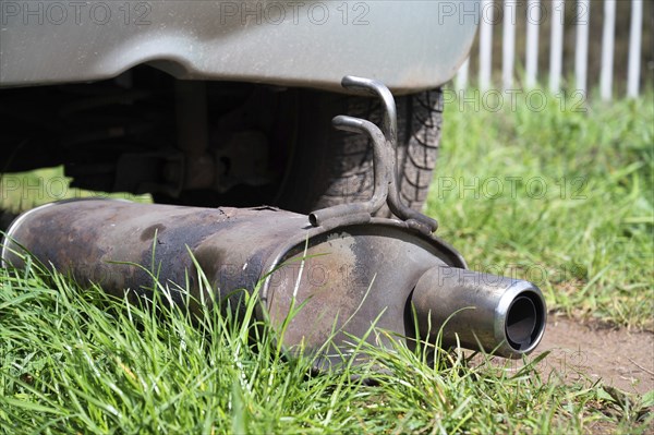 Broken exhaust and muffler of a car, rusted silencer fallen down on the road, breakdown of vehicle