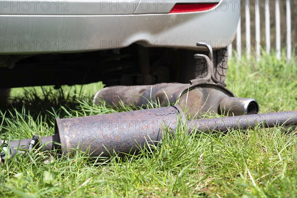 Broken exhaust and muffler of a car, rusted silencer fallen down on the road, breakdown of vehicle