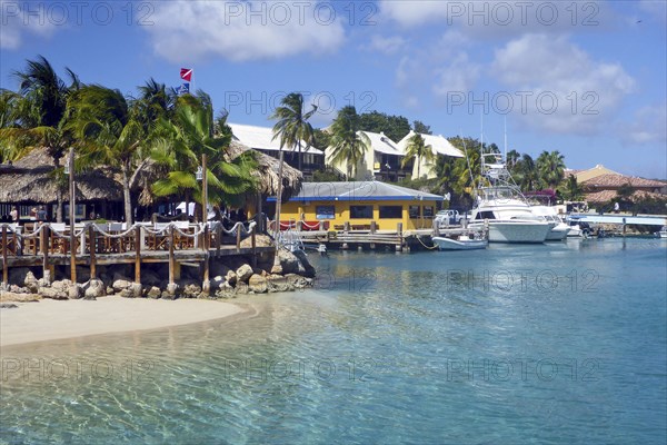 View over shallow narrow inlet channel through lagoon in front of island with sea aquarium on front