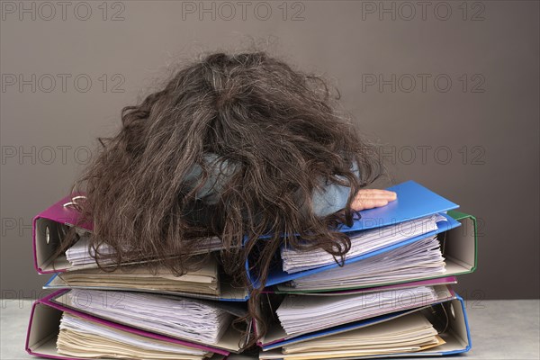 Exhausted tired woman sleeping on a pile of file folders, burnout, stress and overworked, pressure