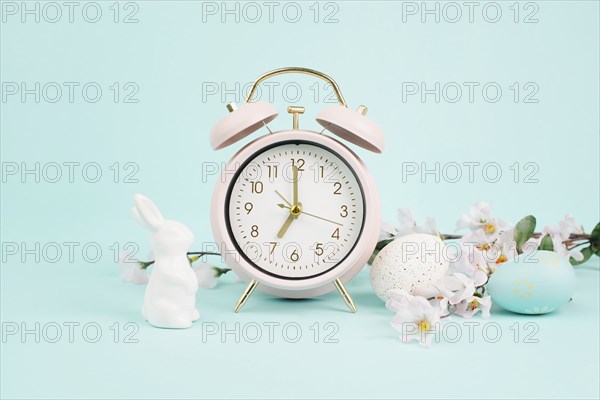 Cute easter bunny or rabbit with an alarm clock, eggs and cherry blossoms, spring holiday, greeting