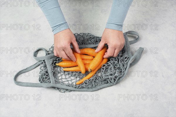 Unpack fresh carrots from a reusable grocery mesh bag, vegetables from the market, healthy food and