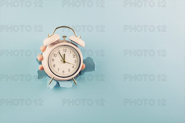 Hand holding alarm clock, torn paper hole, time management, reminder and planning, finish a