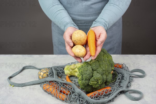 Hands taking potato from the mesh bag with vegetables, shopping grocery, healthy food ingredients,