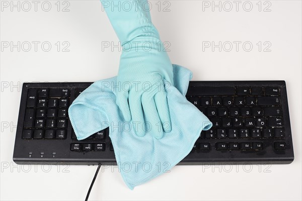 Cleaning computer keyboard in office with a wet wipe rag, dusty and dirty electronic, housework