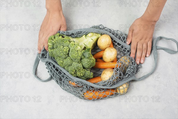 Mesh bag with vegetables, shopping grocery, healthy food ingredients, potato, broccoli and carrots,