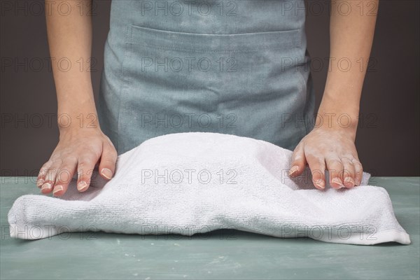 Fresh yeast dough, baker covers bowl with towel for fermentation, bread or pizza, prepare