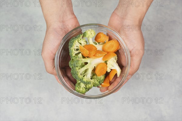 Holding fresh organic broccoli and carrots in the hand, prepare healthy food with vegetables,