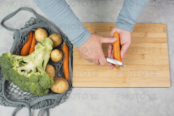 Peel carrot with scraper sharpener, prepare healthy food with vegetables, fresh organic nutrition,
