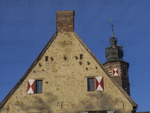 Historic building with crenellated tower and red tiled roof, under a clear blue sky, lüdinghausen,