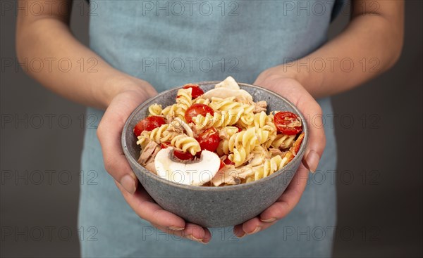 Pasta salad in a bowl, sliced mushroom, tomato, red pepper pieces and tuna, healthy food with