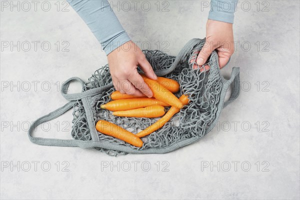 Unpack fresh carrots from a reusable grocery mesh bag, vegetables from the market, healthy food and
