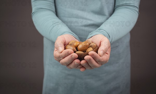 Holding a handful of nuts, mix variety of almonds, hazelnuts and pecan nuts, healthy food and