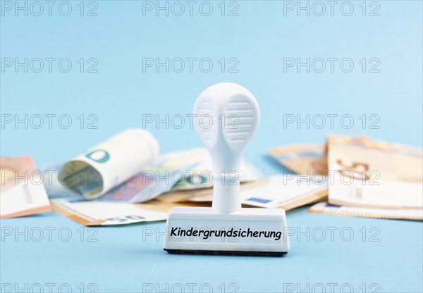 Basic child benefit stands in german language on the stamp, Euro banknotes in the background, new