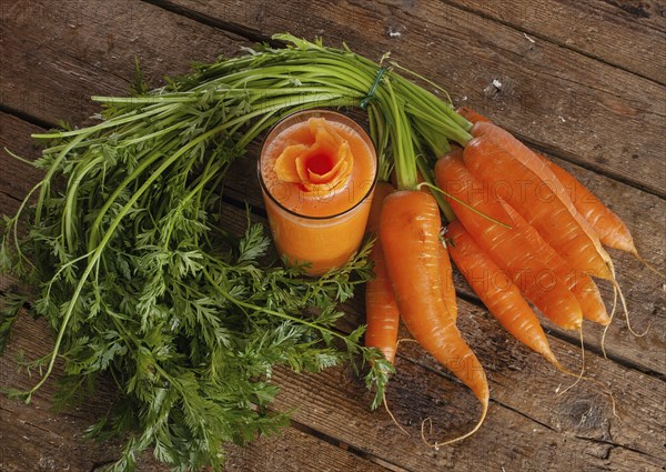 Fresh carrot juice glass with fresh organic carrots on wooden table