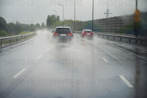 Cars driving on the road, heavy rain, low visibility, slippery street, dangerous storm, overcast