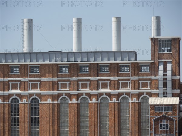 Large red brick building with several large chimneys and many windows under a blue sky, Lisbon,