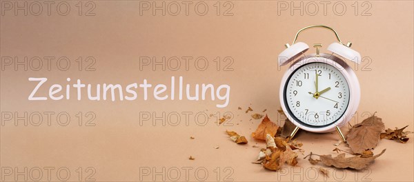 Alarm clock with autumn foliage, end of daylight saving time in fall, winter time changeover stands