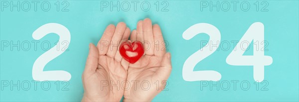 New year 2024, calendar date, red heart in the palms of the hands, charity concept, new goals and